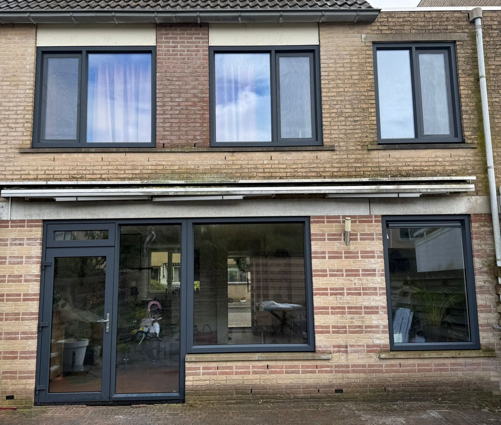 Antracietgrijze kunststof kozijnen over de hele voorgevel van een rijwoning